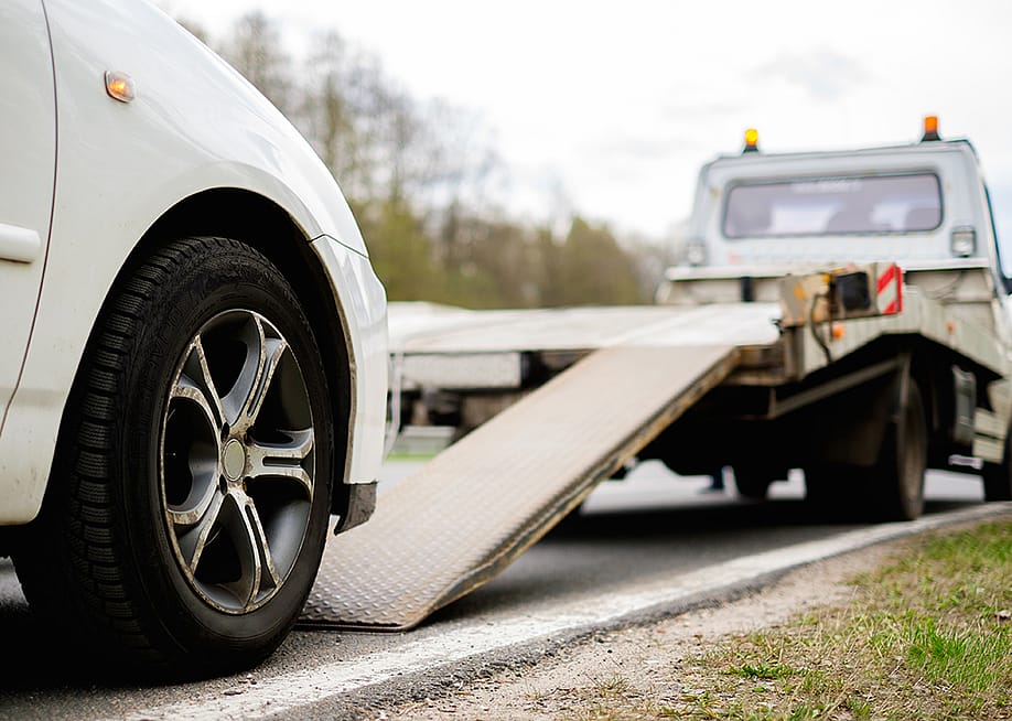 A broken car being loaded on a tow truck on roadside. — Nejron Photo // Shutterstock