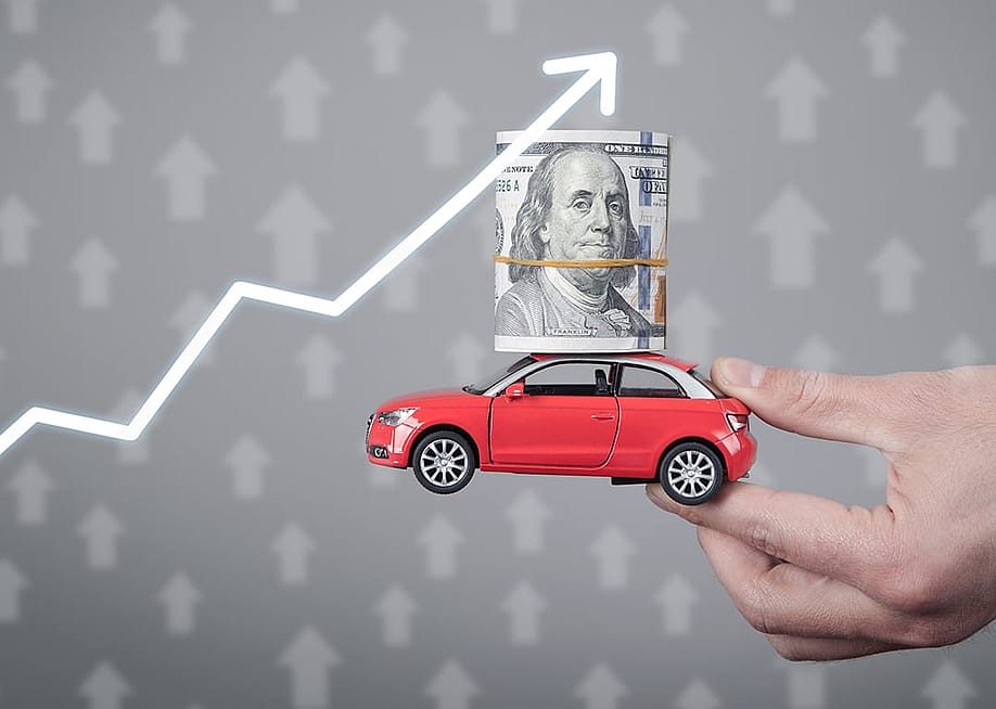 A miniature car with a dollar on top held up with an upward arrow as a concept of rising prices. — ANDRANIK HAKOBYAN // Shutterstock
