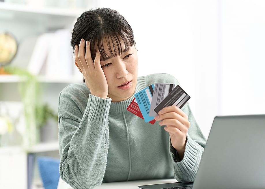 A woman looking worried at her four credit cards. — mapo_japan // Shutterstock