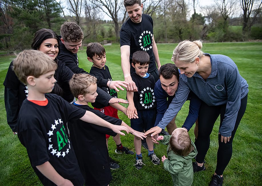 A group of young kinds with their parents form a circle to join hands before a game. — Athletes Untapped