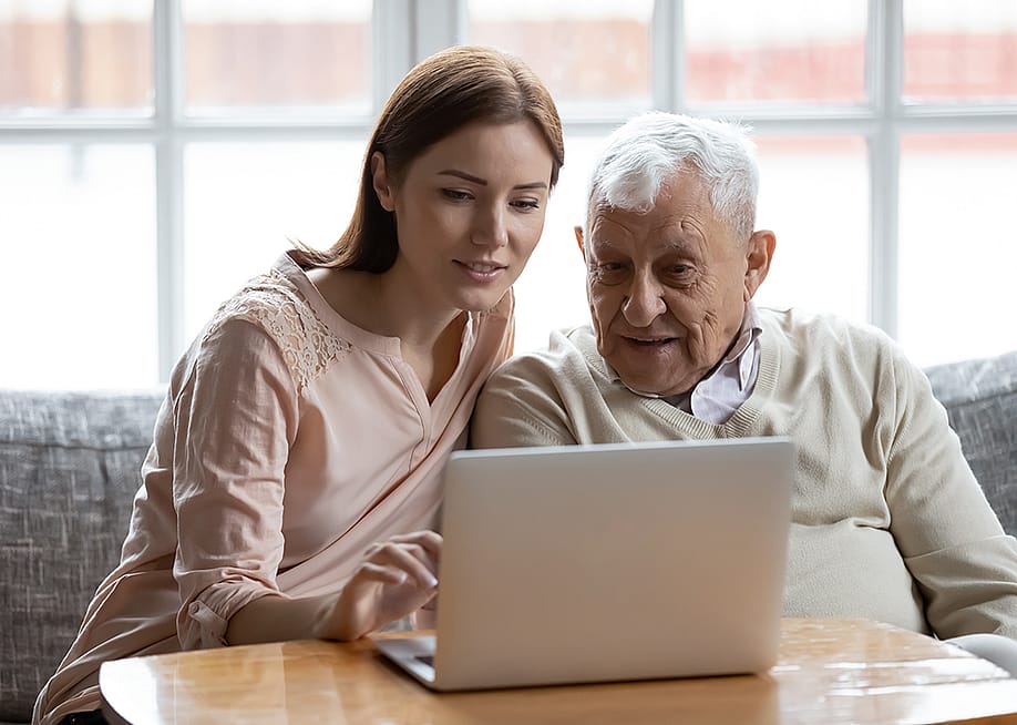 A senior man with his caregiver browsing the internet using a laptop. — fizkes // Shutterstock