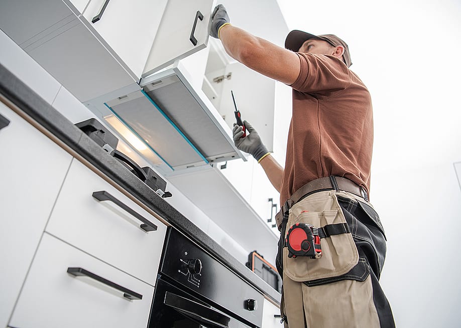 A cabinetmaker finishing a white, modern cabinet installation — Virrage Images // Shutterstock