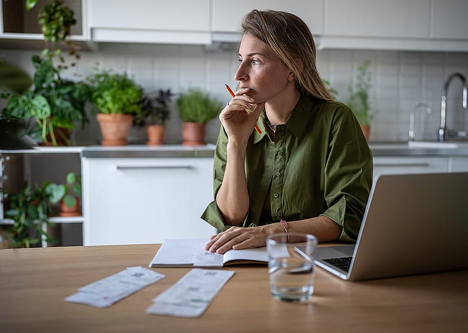A pensive woman at home working on accounting documents. — DimaBerlin // Shutterstock
