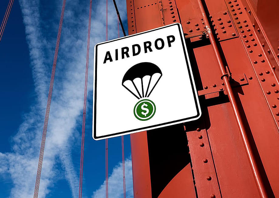 Signage showing "Airdrop" with a symbol of a cryptocurrency token attached to a parachute. — Cryptographer // Shutterstock