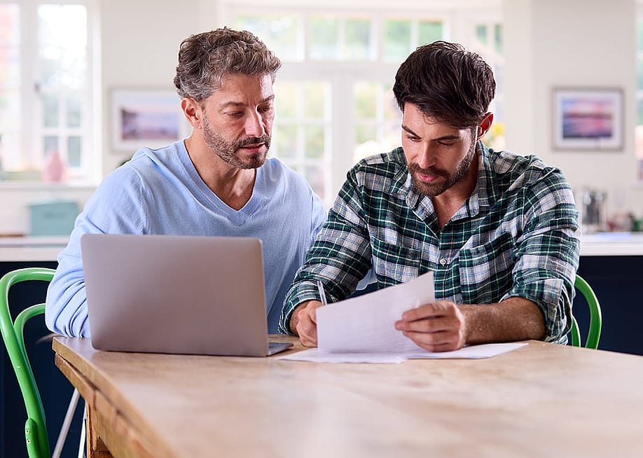 A gay couple at home checking finance documents. — Monkey Business Images // Shutterstock