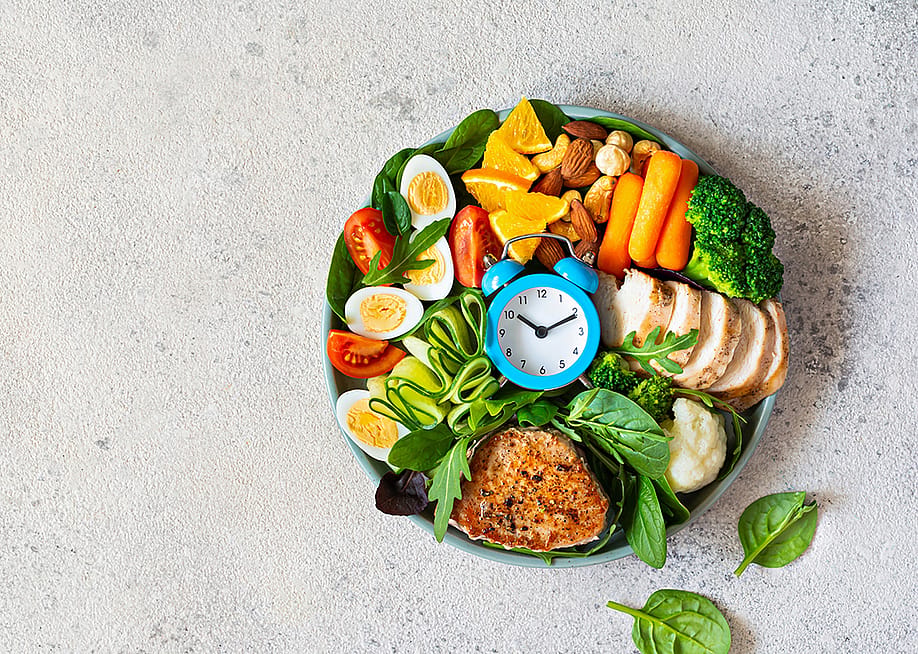 A bowl of vegetable meat with meat, fish, eggs, and a clock at the middle. — DROBOT VIKTORIIA // Shutterstock