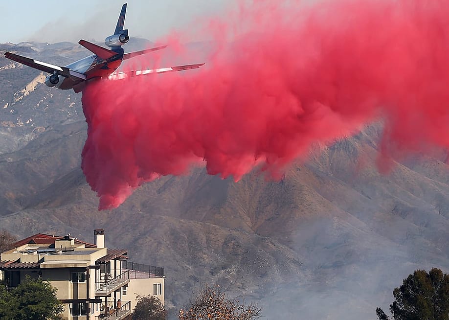 A firefighting aircraft drops the fire retardant Phos-Chek near homes during the Palisades Fire on January 10, 2025 in Topanga, California. — Mario Tama // Getty Images