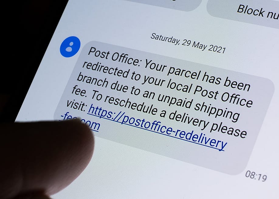 Phone displaying a USPS scam text message with a link. — mundissima // Shutterstock