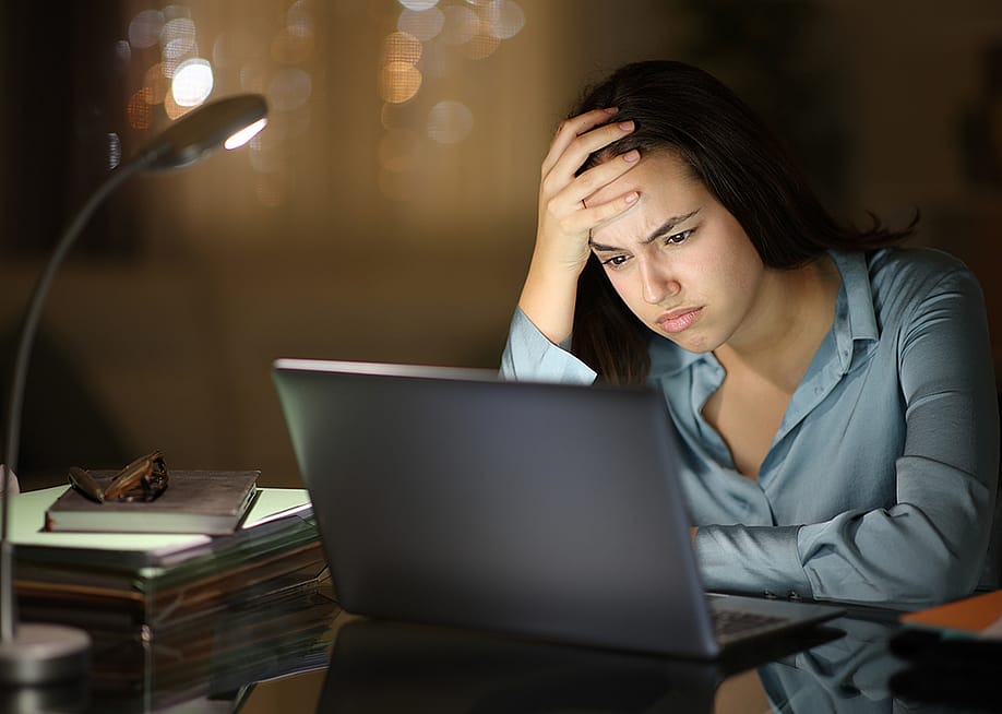 A young female professional frustratingly looks at her laptop at work. — Pheelings media // Shutterstock