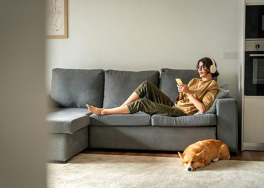A young woman lying on couch while listening to music with her headphones. — Stock 4you // Shutterstock