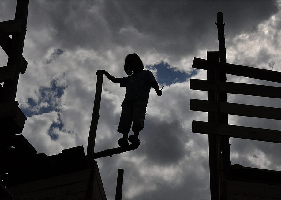 Silhouette of one of the children standing on the edge of an abandoned wooden fort. — Courtesy of Kolle 37
