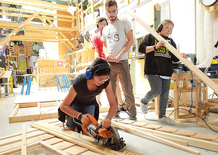 Brightworks students — A group of Brightworks students work to cut and assemble wooden parts of a project.