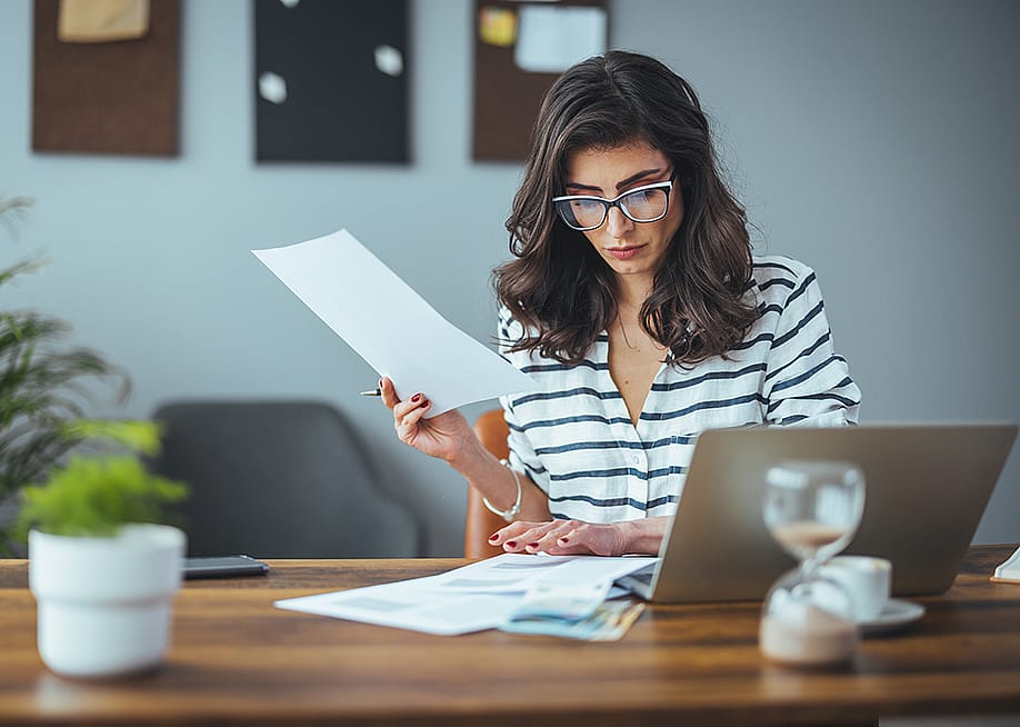 A businesswoman reading finance documents in an office. — Dragana Gordic // Shutterstock
