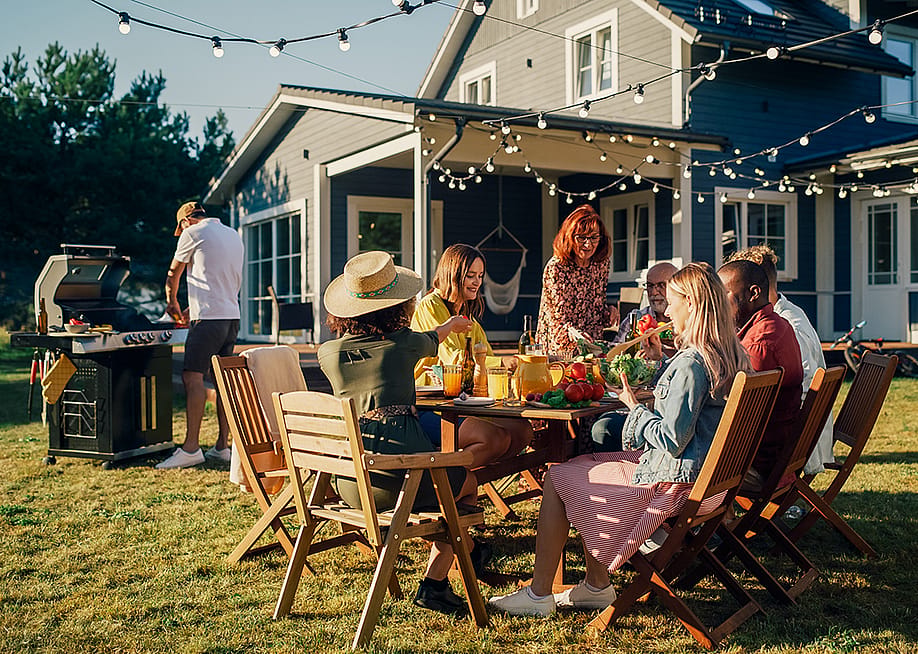 Family and friends dining outside a home during a barbecue dinner party. — Gorodenkoff // Shutterstock