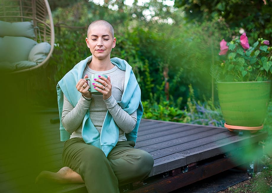 A breast cancer patient sitting on a garden patio with a cup of coffee in her hands. — ABO PHOTOGRAPHY // Shutterstoc