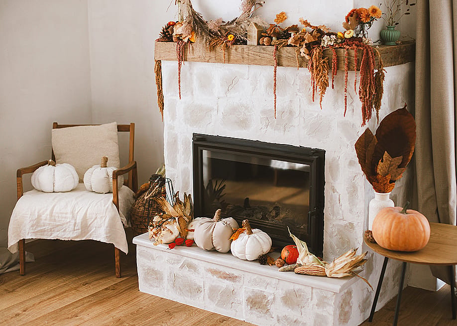 Fireplace corner of a living room with fall season decoration. — Bogdan Sonjachnyj // Shutterstock