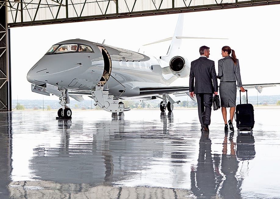 A pair of business people walking towards a private plane. — Juice Flair // Shutterstock