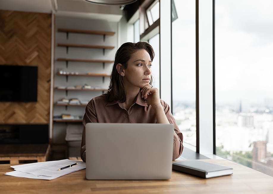 A young businesswoman in an office looking out the window. — fizkes // Shutterstock