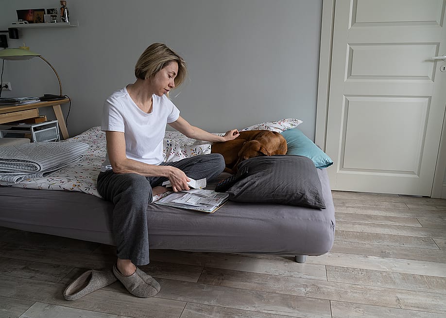 Single middle-aged woman looking at a pile of bills. — DimaBerlin // Shutterstock
