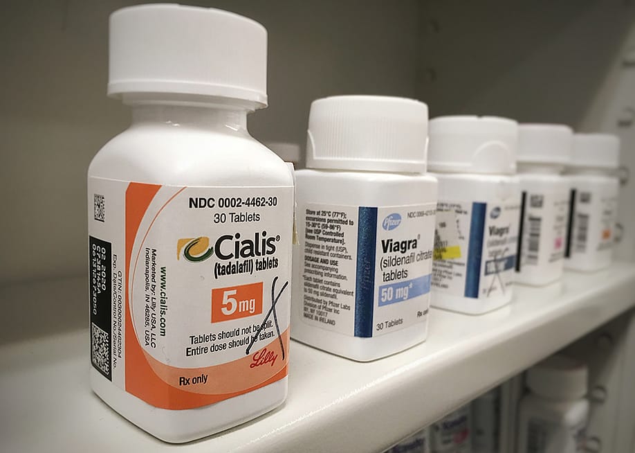 Bottles of Cialis and Viagra on a shelf. — PureRadiancePhoto // Shutterstock