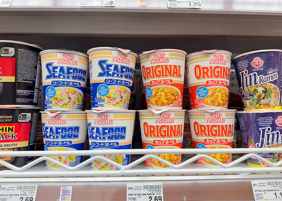 Assorted Cup Noodles packages on a grocery store shelf. — The Image Party // Shutterstock
