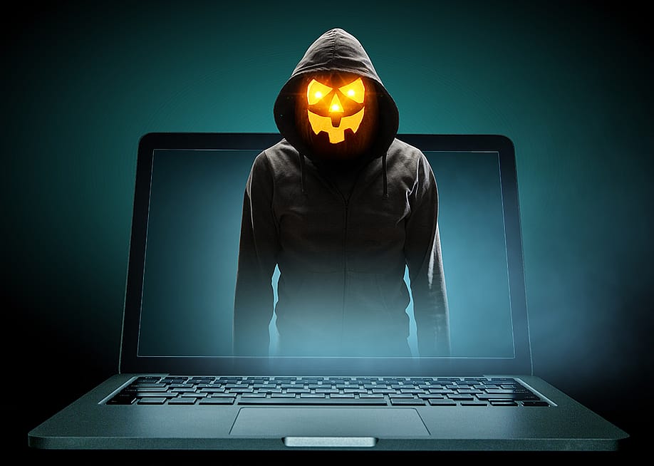 Anonymous man with a Halloween pumpkin head illustrated as emerging from a laptop. — Sergey Nivens // Shutterstock