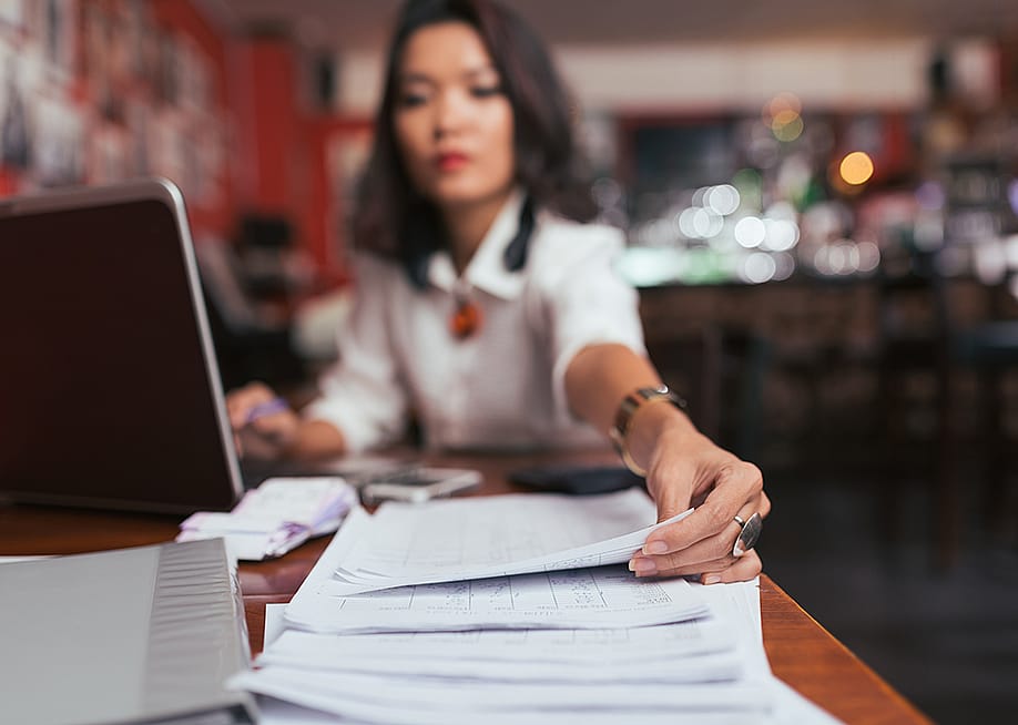 A female business owner reaches out for finance documents. — Dragon Images // Shutterstock