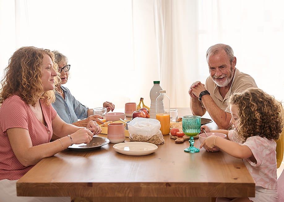 A happy family including grandparents seated in a table during breakfast. — alvarog1970 // Shutterstock