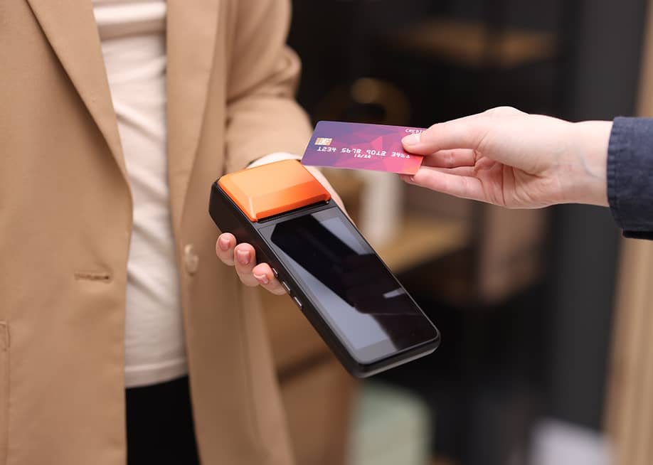 Person taps a business credit card on a payment terminal. — New Africa // Shutterstock