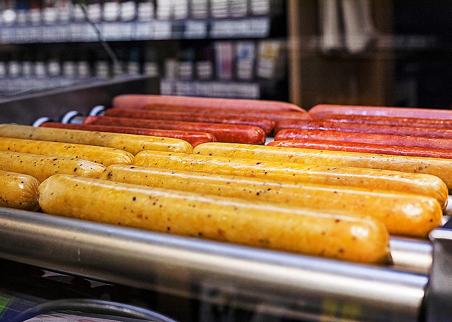 Hot dogs on a roller grill in a gas station. — namaki // Shutterstock