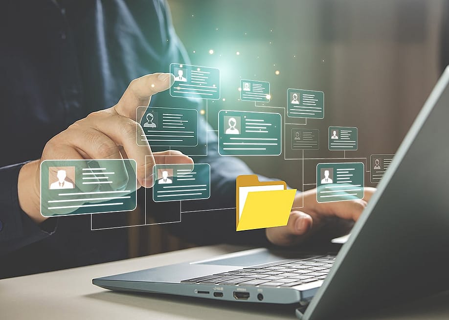 Businessperson using a laptop hovers at graphic illustration of a personal file management software. — Midnight Studio TH // Shutterstock