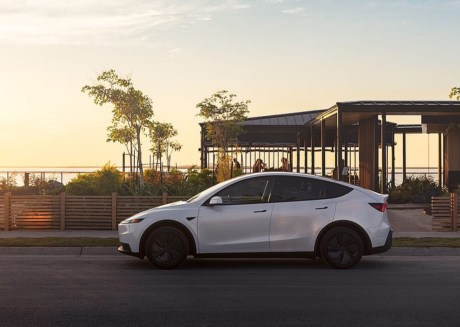 A white Tesla Model Y on the road. — Tesla