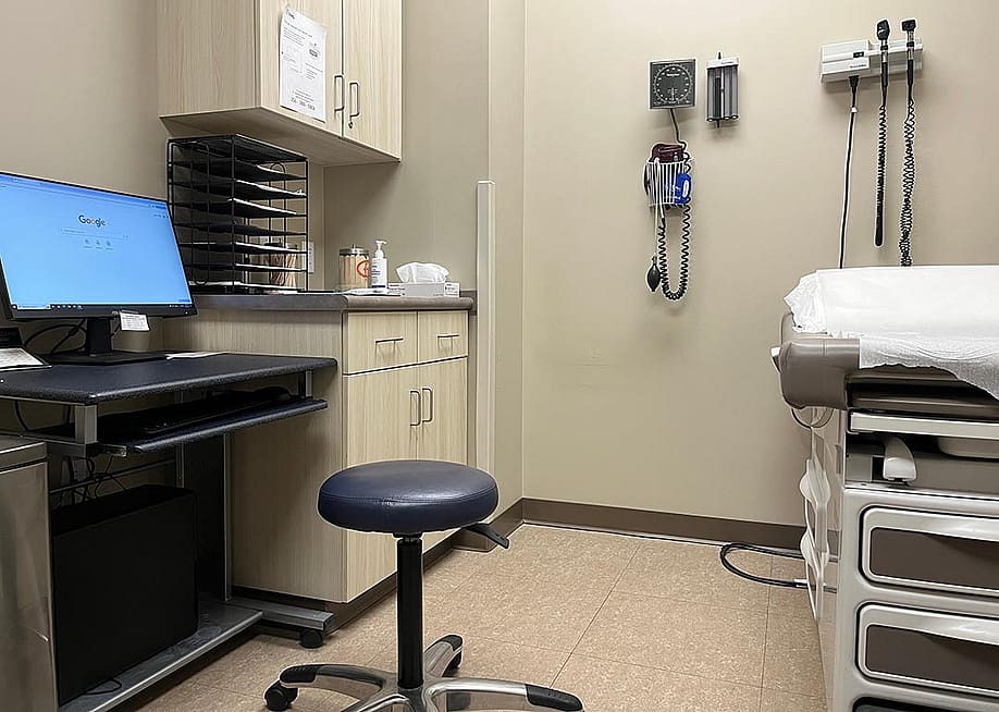 An empty examination room in a clinic with a computer, exam tamble, stool and various medical devices on the wall in Muscle Shoals, Alabama USA. — Luisa P Oswalt // Shutterstock