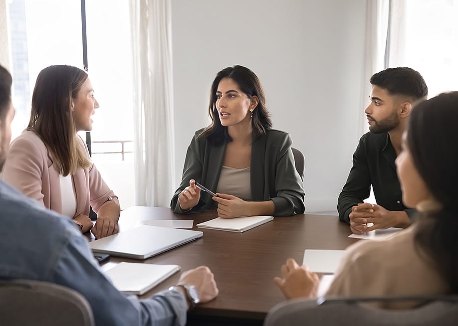 A business team seated around a conference table. — fizkes // Shutterstock