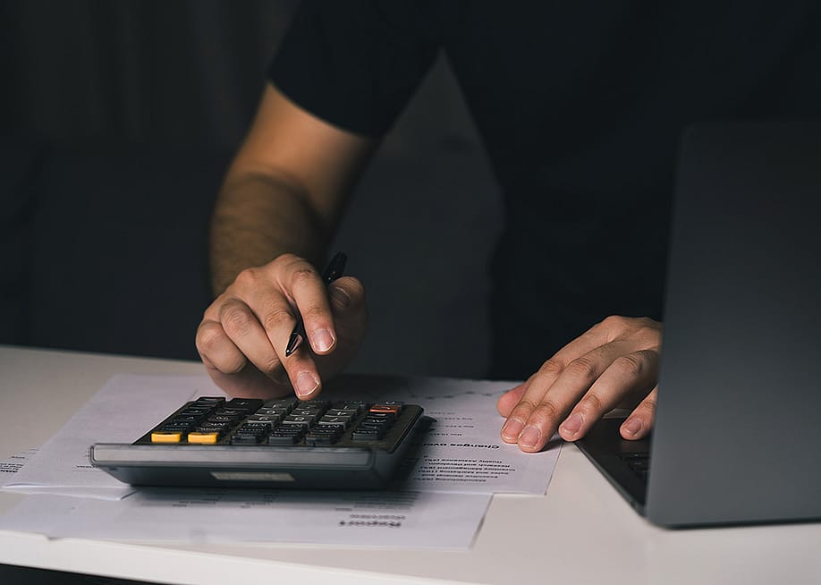 A man uses a calculator to compute monthly expenses. — wutzkohphoto // Shutterstock