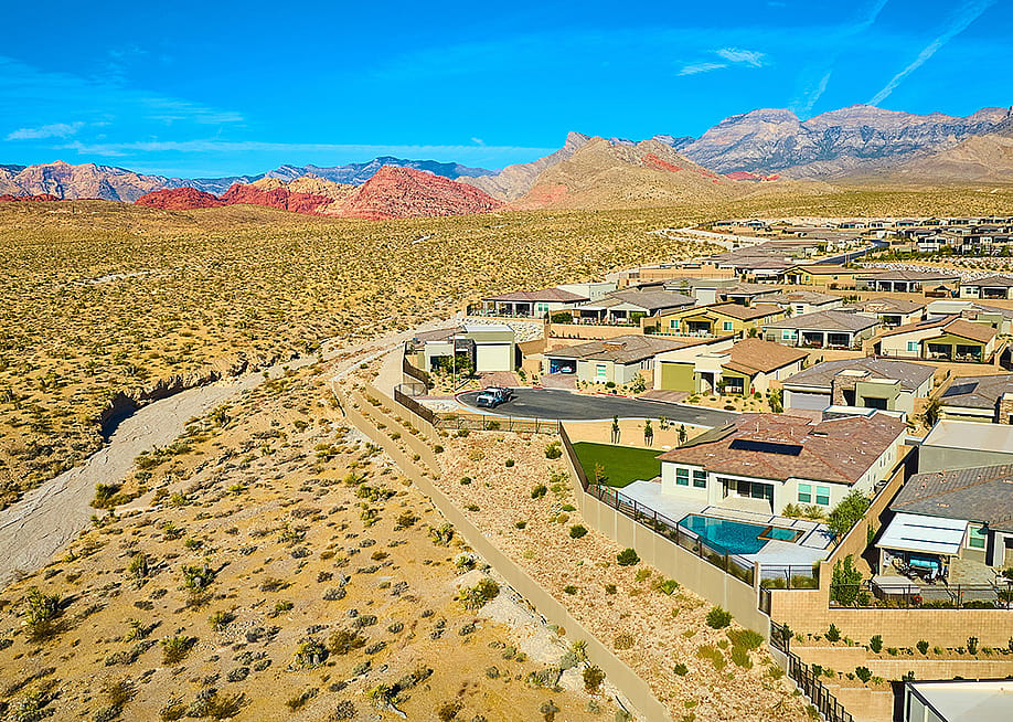 An aerial view of a modern suburban residential neighborhood situated in a mountainous desert area. — Nicholas J Klein // Shutterstock