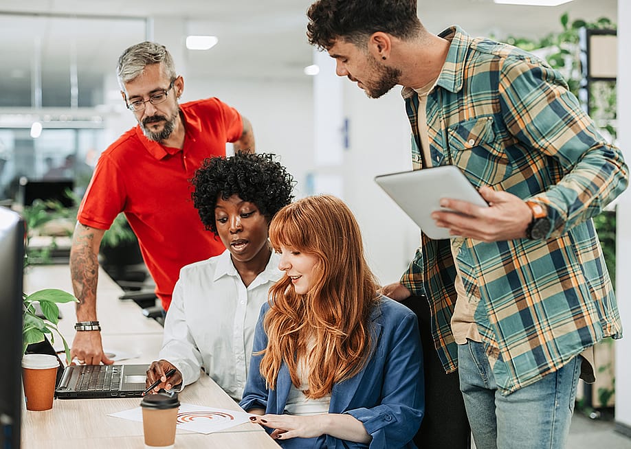 A diverse four-member team sharing ideas in an office. — Zamrznuti tonovi // Shutterstock