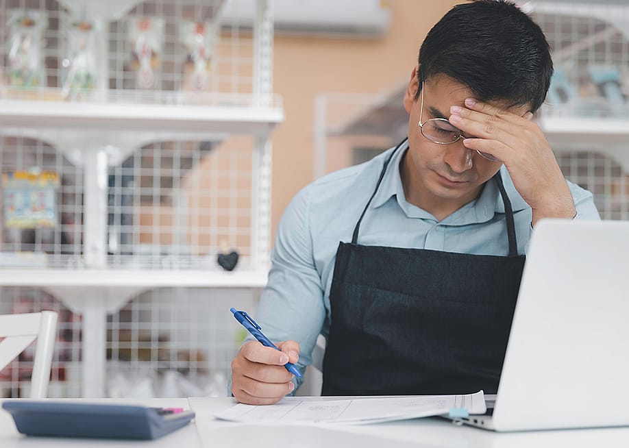 A male small business owner feeling stressful while reading finance documents. — Dan76 // Shutterstock