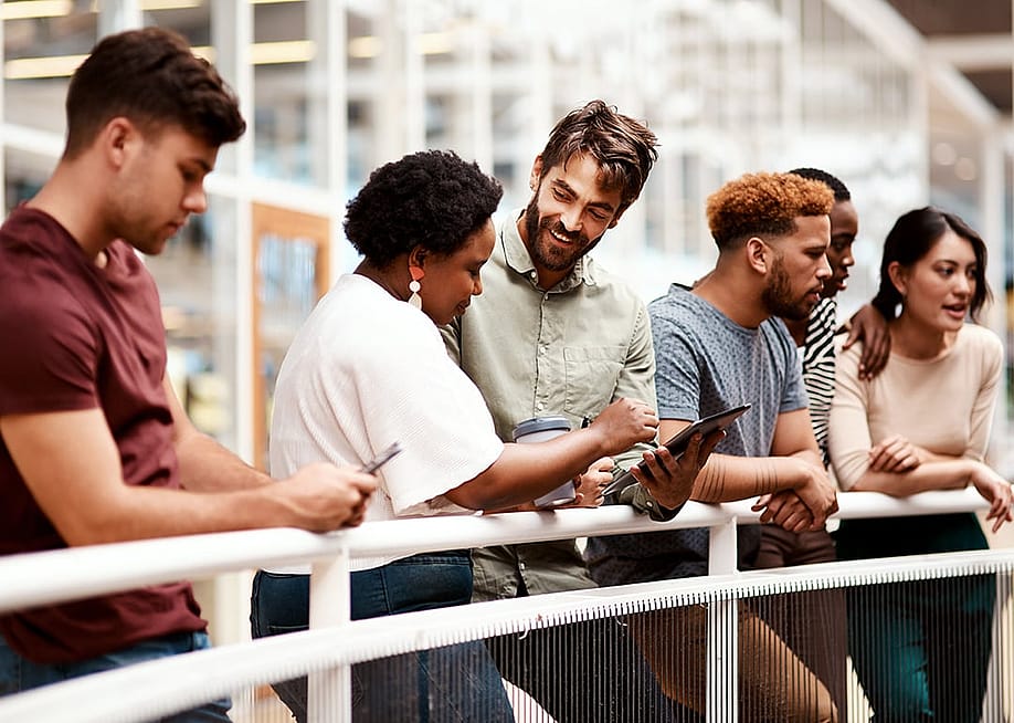 An office team engaged in discussion while standing by a railing. — PeopleImages // Shutterstock