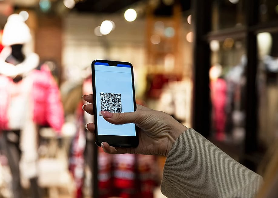 A person scans a QR code in a smartphone in front of a clothing store. — Deman // Shutterstock