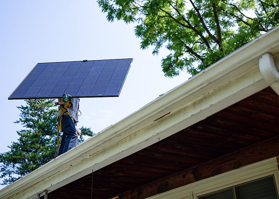 Michael Reimann, installer with Lumina Solar, carries a large panel and his face is not visible while installs solar panels on the roof of a home in Kensington, MD on July 3, 2025. — Maansi Srivastava for The Washington Post via Getty Images