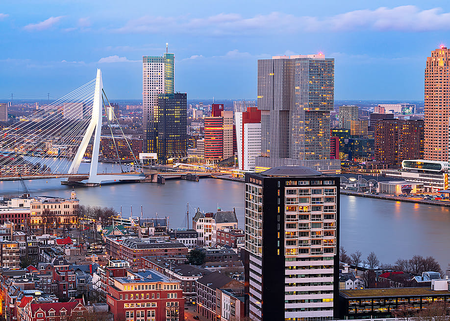 View of the Rotterdam city skyline over the Nieuwe Maas River during twilight in Netherlands. — Sean Pavone // Shutterstock