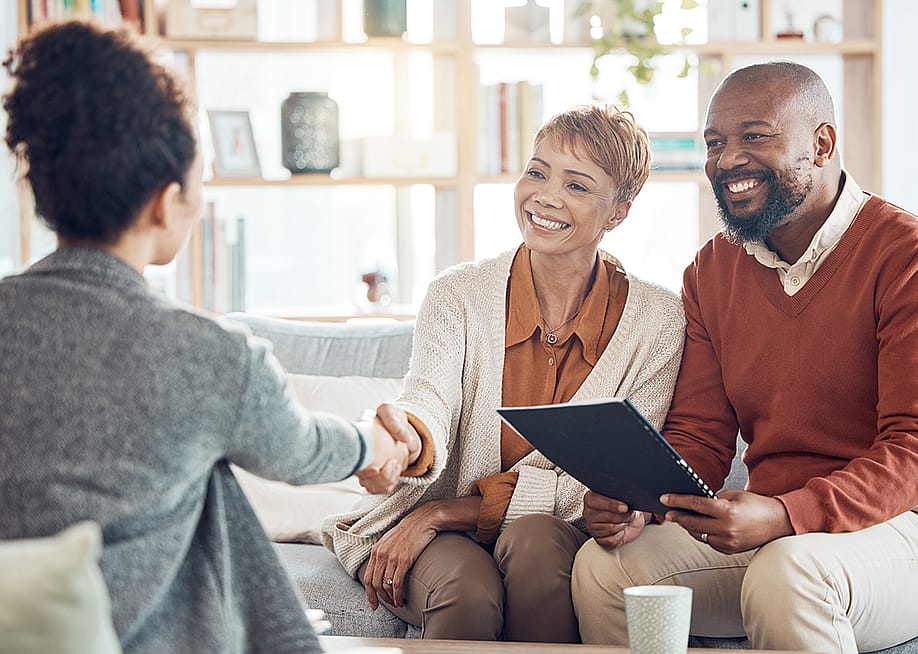 A couple shaking hands with a financial advisor. — PeopleImages // Shutterstock