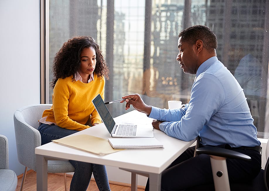 A young woman engaged in a discussion with a financial advisor in an office. — Monkey Business Images // Shutterstock