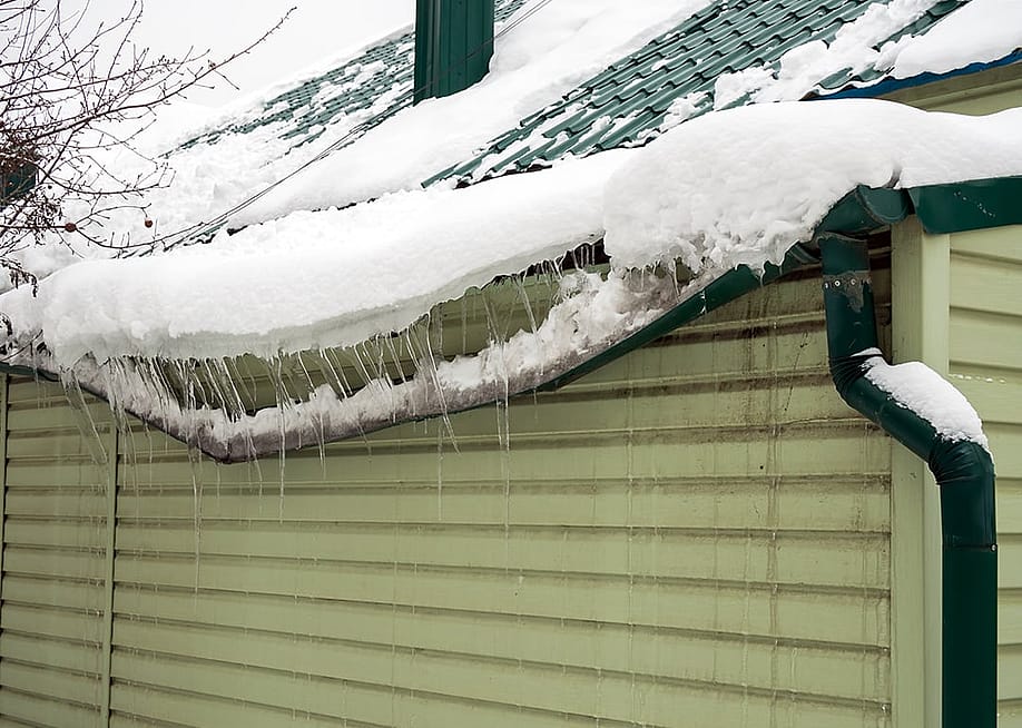 Heavy snow destroys as it accumulated on a home's drainage system. — VPales // Shutterstock