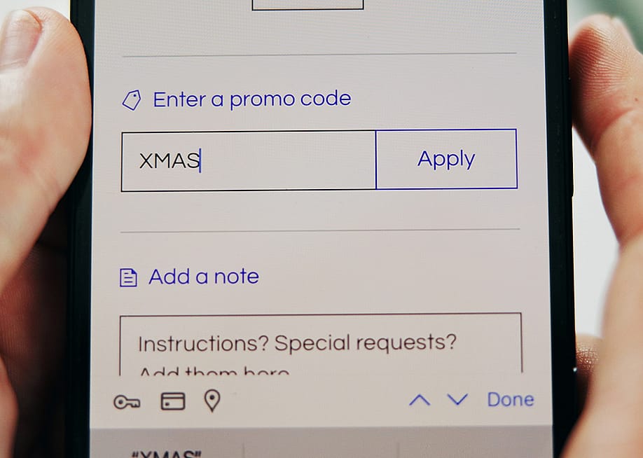 A Christmas promo code added into a shopping app checkout page. — PeopleImages // Shutterstock