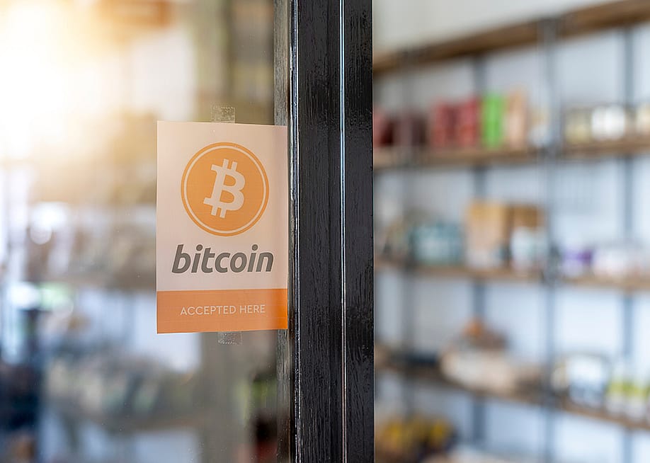 A entrance door sign showing 'Bitcoin (is) accepted here)'. — Joao Serafim // Shutterstock