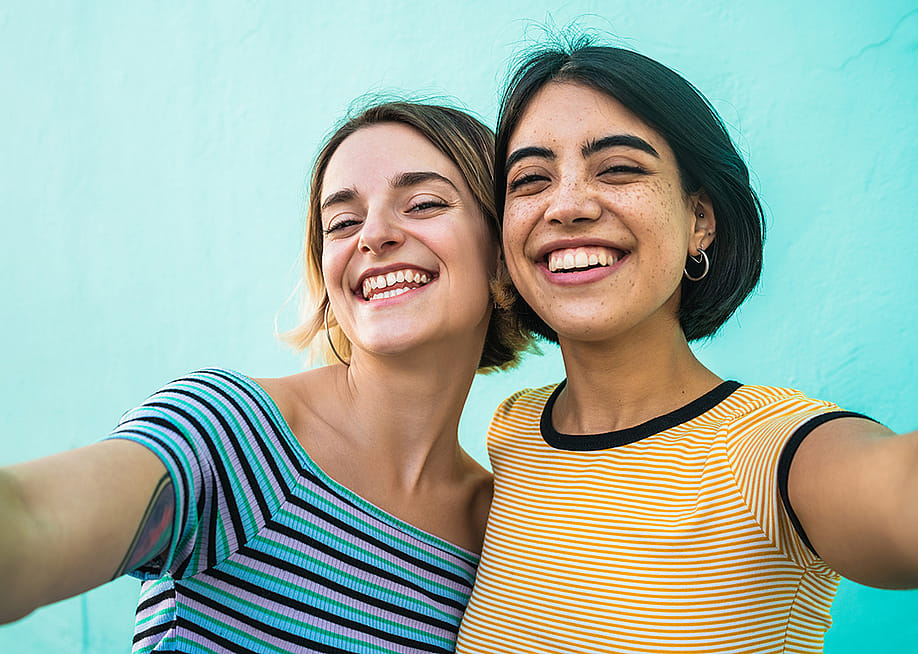 Two young women smiling for a selfie-style photograph. — Mix Tape // Shutterstock
