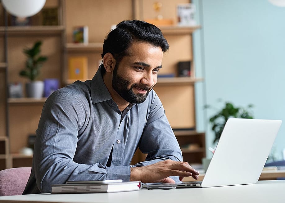 A happy business man working with a laptop in his home office. — Ground Picture // Shutterstock