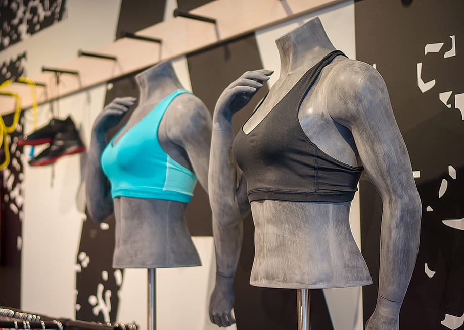 Different colors of women's sports bra displayed on torso mannequins at a sports clothing store. — Andrey Burstein // Shutterstock